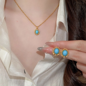 Close-up of vintage gold necklace and earrings set featuring oval turquoise and zircons