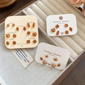 Dettaglio di orecchini a forma di orso e croissant su scheda settimanale in scatola