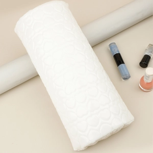 Close-up of a white heart-quilted PU leather nail hand rest with manicure accessories