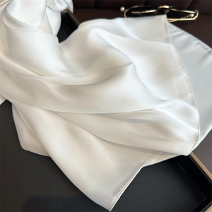 Close-up of white silk scarf showing soft satin texture and elegant drape effect