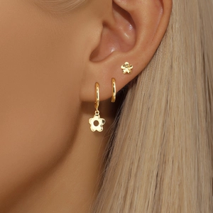 Ensemble de trois boucles d'oreilles fleurs dorées portées avec créoles
