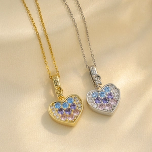 Gold and silver heart necklaces with colorful zircon gems on a beige silk background
