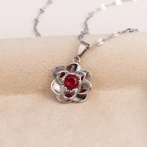 Macro detail of silver rose pendant with red gemstone on a fine O-chain necklace