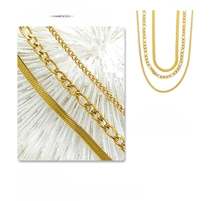 Detailed macro view of gold-plated triple-layer Figaro and snake chain necklace set