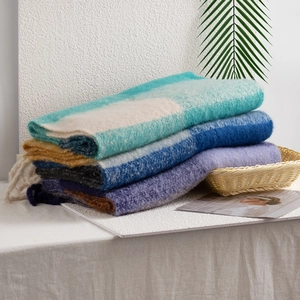 Soft mohair plaid scarves in blue green and purple gradients neatly folded on a table