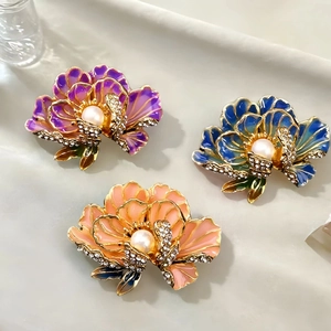 Elegant floral brooches set with crystal rhinestones and pearls on light gray surface