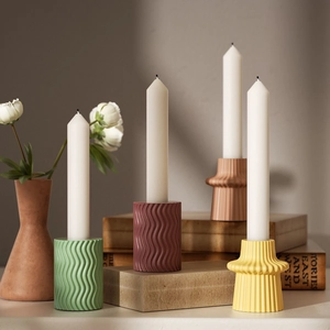 Close-up of geometric striped resin candle holders in matte green and terracotta colors
