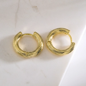 Classic twisted texture gold-plated hoop earrings on white marble background