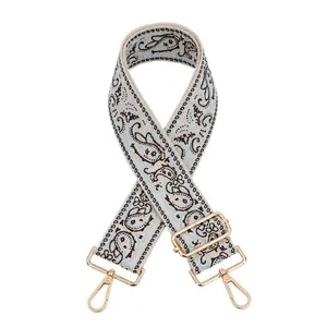Detail of adjustable blue paisley jacquard bag strap with gold metal hooks and hardware