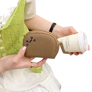 Brown lychee leather cat coin purse with gold zipper held by a model with coffee