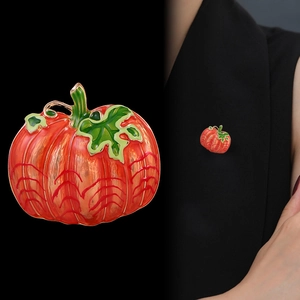 Gold-plated enamel pumpkin brooch with orange and red tones shown on black clothing
