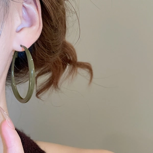 Detail shot of large olive green geometric resin hoop earring on female model