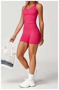 Set yoga rosa rosso con crop top a vogatore e pantaloncini a vita alta indossati da modella
