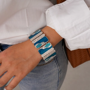 Close-up of wide blue enamel bangle with hammered metal texture worn on wrist