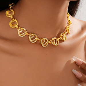 Close-up of golden snake chain links with sparkling crystals and red gemstone eyes