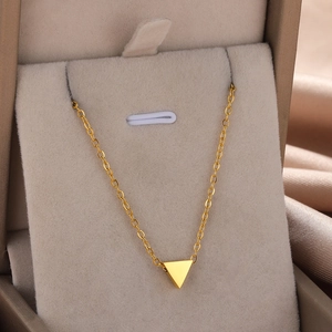 Detailed close-up of a golden polished triangle pendant on a delicate chain necklace