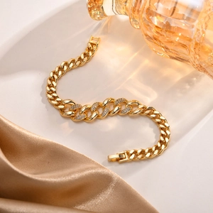 Detailed close-up of a gold-plated cubic zirconia curb chain bracelet on satin fabric