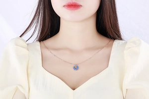 Detail of rose gold bee coin necklace with blue enamel pendant worn on neck