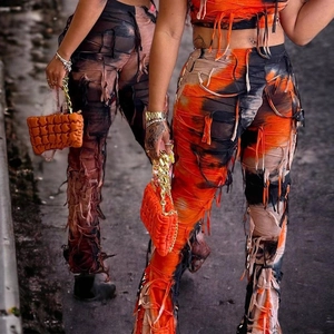 Dettaglio del set streetwear tie-dye arancione con orlo a frange e ritagli effetto usurato