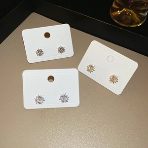 Macro view of three pairs of silver and gold snowflake zircon stud earrings on display card