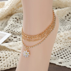Detail of layered gold anklet with sparkling rhinestones and a white daisy floral charm
