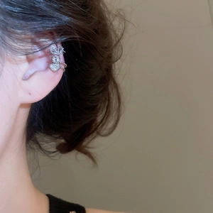 Close-up of a silver zircon ear cuff featuring heart and crown designs worn on the helix