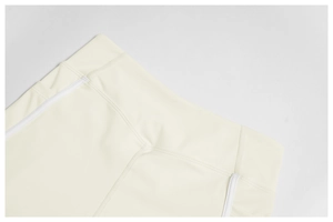 Detail of high-waist cream yoga shorts featuring fine flatlock seams and white piping