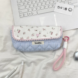 Detailed close-up of floral quilted pencil case with pom-pom trim and pink handle