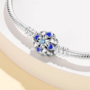 Close-up of flower charm with blue enamel heart and crystals on a silver snake chain