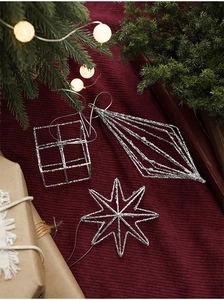 Detail view of silver glitter star and geometric Christmas ornaments on red background