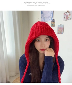 Gros plan du bonnet en grosse maille rouge avec tresses et texture de laine épaisse