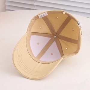 Detail view of beige cotton baseball cap featuring 6-panel stitching and metal buckle