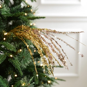 Sparkling gold and rose gold sequin branch ornaments on a Christmas tree with warm lights