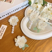 Detailed view of white tulip hair clips with pearls on a rustic wooden background