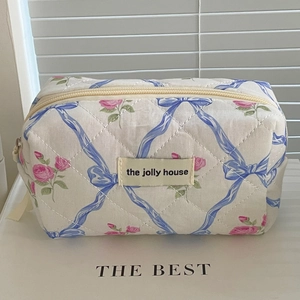 Close-up of quilted floral cosmetic bag with pink roses and blue ribbon bow print