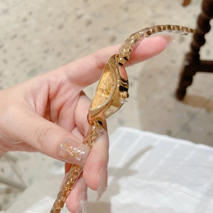 Détail du cadran triangulaire doré de luxe et bracelet chaîne au poignet d'une femme