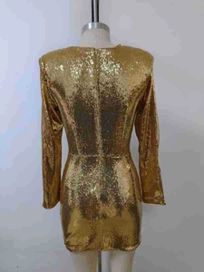 Détail de paillettes dorées scintillantes sur la robe courte sexy à manches longues