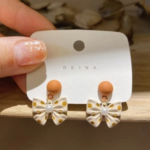 Detail of retro bow earrings with polka dots and faux pearl on a display card