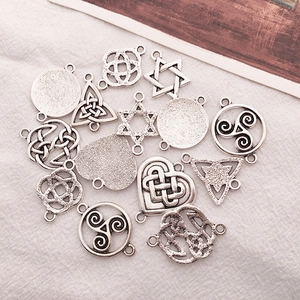 Flat lay of assorted silver Celtic knot pendants and geometric charms on white fabric