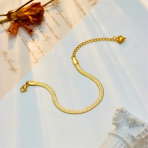 Elegant gold snake chain bracelet with heart pendant on minimalist decorative display