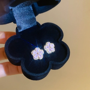Detail of pink floral zircon earrings with gold trim displayed on a black velvet case