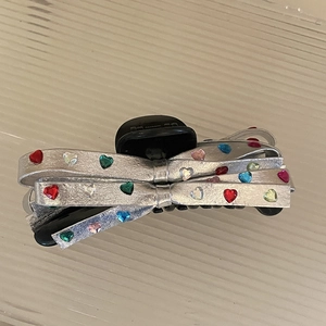 Pinza per capelli a fiocco argento con strass a cuore colorati su legno chiaro