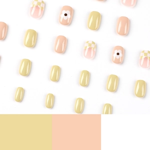 Short square press-on nails with yellow floral patterns and checkerboard design