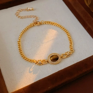 Close-up of gold-plated bracelet featuring oval tiger eye stone and zircon micro-pave