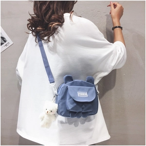 Blue canvas crossbody bag with cute bear ears and a plush charm shown on a model