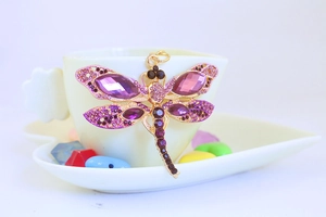 Macro shot of purple crystal dragonfly keychain with gold plating and rhinestones
