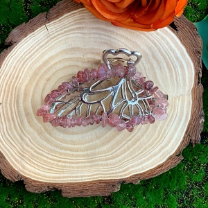 Detail of leaf-shaped silver hair clip with pink crystal stones on wooden background