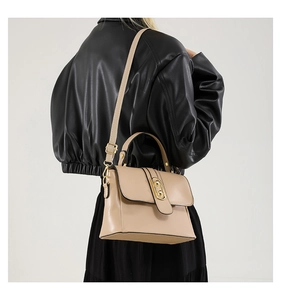 Detail of apricot flap handbag with gold twist lock and adjustable shoulder strap