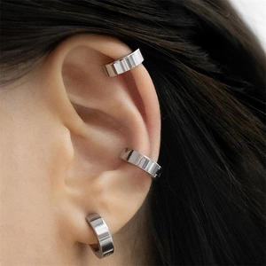 Close-up of minimalist silver stainless steel ear cuffs worn on three ear positions