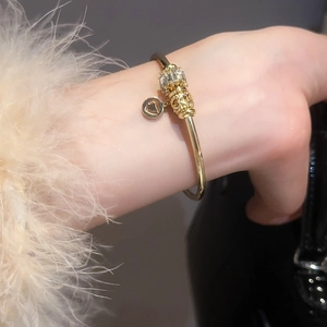Détail de bracelets dorés avec breloque en zircon rectangulaire et pendentif en cœur